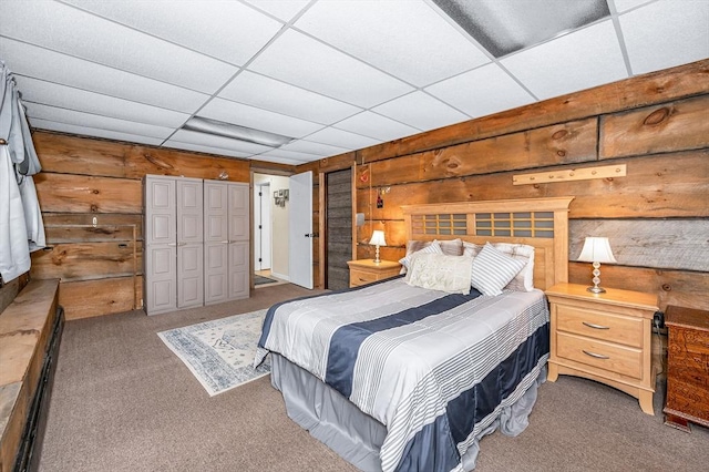 carpeted bedroom with wooden walls and a drop ceiling