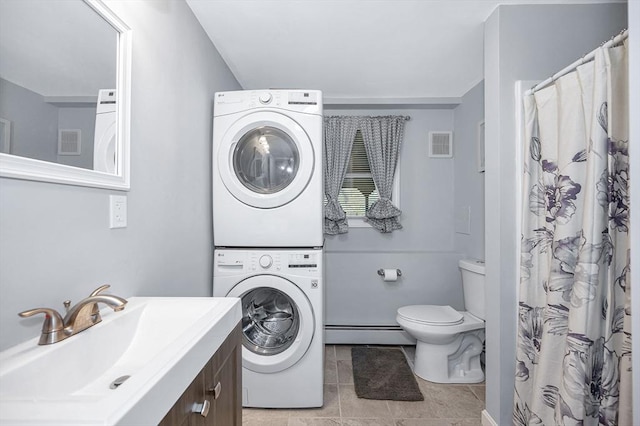 full bath featuring stacked washer and clothes dryer, a baseboard radiator, toilet, vanity, and tile patterned floors