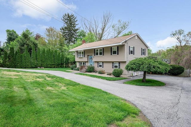 split foyer home with a front lawn and a chimney
