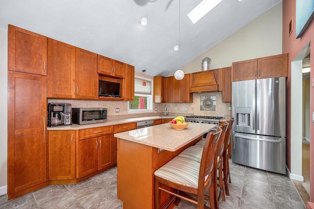 kitchen with stainless steel appliances, lofted ceiling, decorative backsplash, a sink, and brown cabinetry