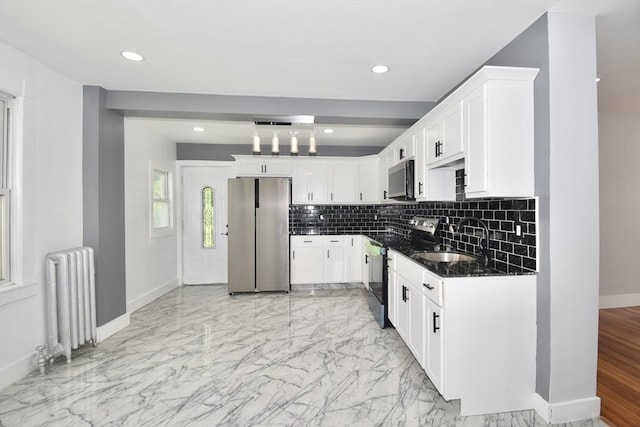 176 N Blvd, West Springfield, MA 01089 - kitchen with appliances with stainless steel finishes, radiator, backsplash, white cabinetry, and light marble finish floors