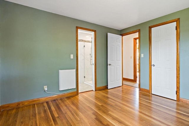 unfurnished bedroom with baseboards, light wood-style floors, and connected bathroom