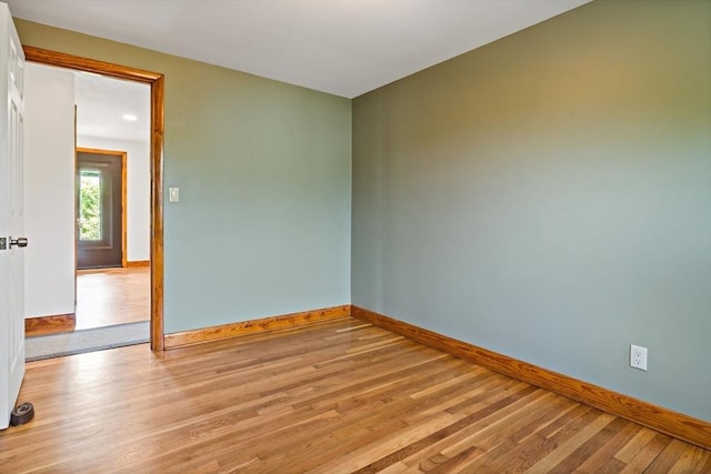 empty room featuring baseboards and light wood finished floors