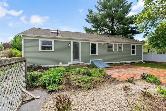 rear view of property featuring a patio, fence, and a shingled roof