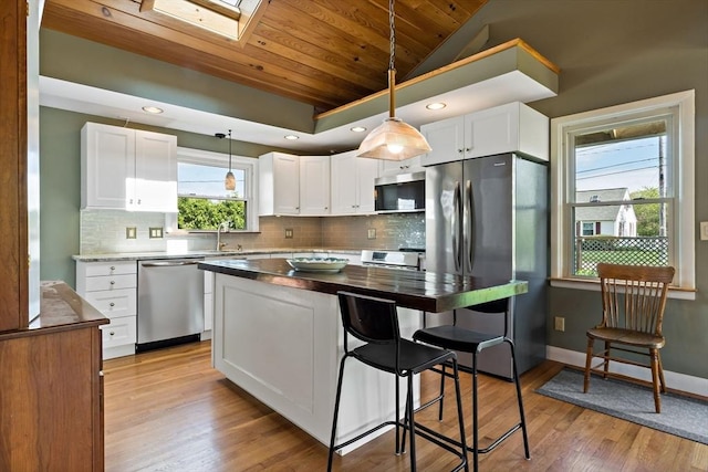 kitchen featuring stainless steel appliances, wooden ceiling, lofted ceiling, white cabinetry, and decorative light fixtures