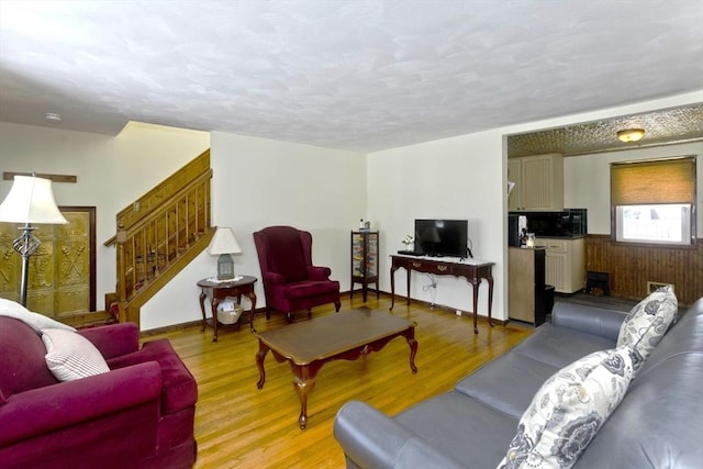 living room with baseboards, stairway, and light wood finished floors