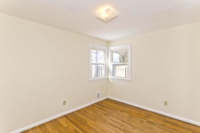 empty room featuring visible vents, baseboards, and wood finished floors