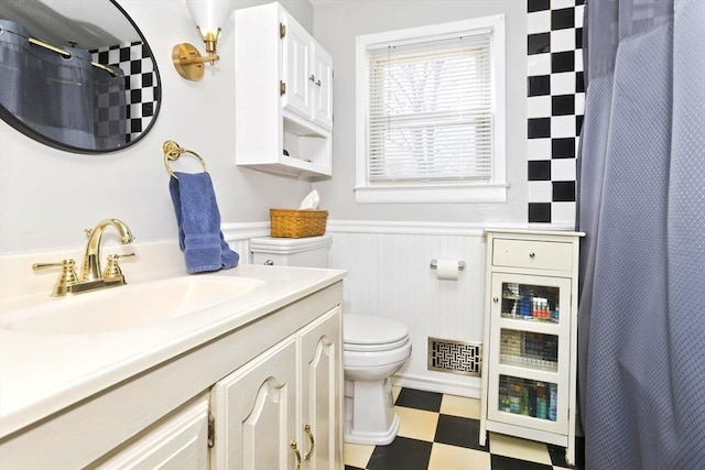 bathroom with visible vents, wainscoting, toilet, tile patterned floors, and vanity