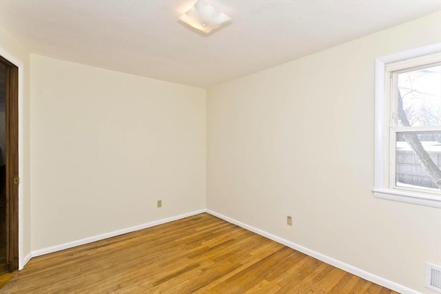 unfurnished room featuring light wood finished floors, visible vents, and baseboards