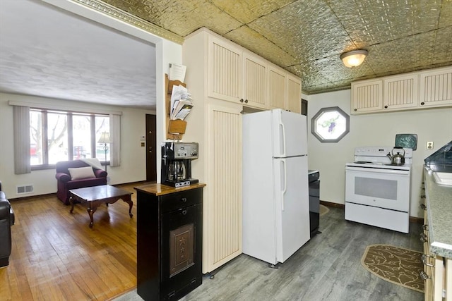 kitchen with white appliances, wood finished floors, visible vents, baseboards, and an ornate ceiling