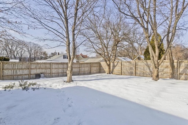 snowy yard with a fenced backyard