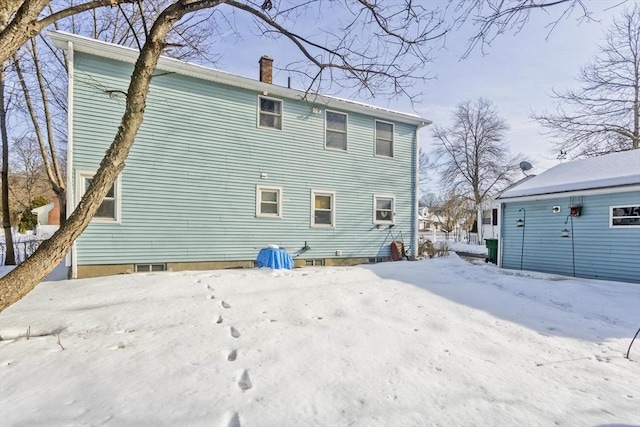 snow covered house featuring a chimney