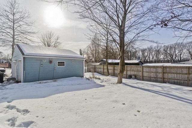 snowy yard with an outbuilding and fence