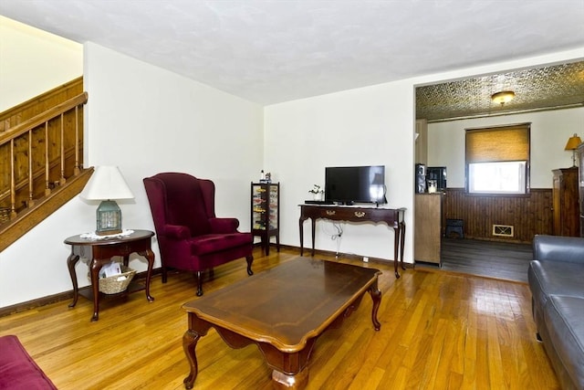 living area featuring wooden walls, a wainscoted wall, stairway, and wood finished floors