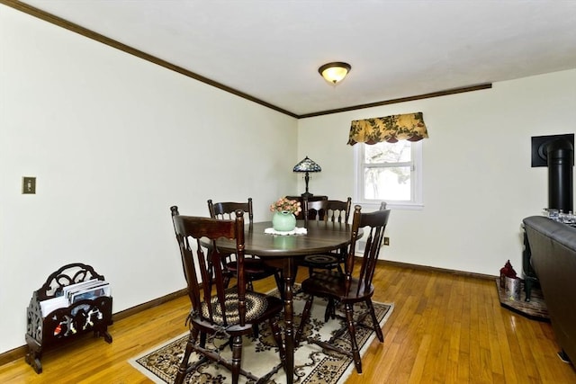 dining area with baseboards, hardwood / wood-style floors, a wood stove, and crown molding