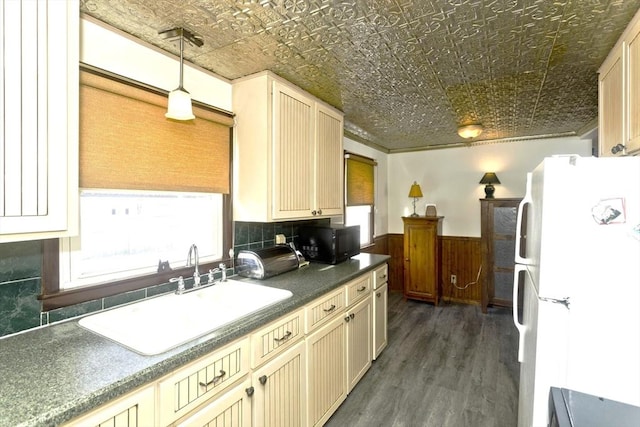 kitchen with an ornate ceiling, a wainscoted wall, dark countertops, freestanding refrigerator, and a sink