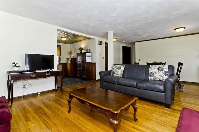 living area featuring ornamental molding, a textured ceiling, baseboards, and wood finished floors