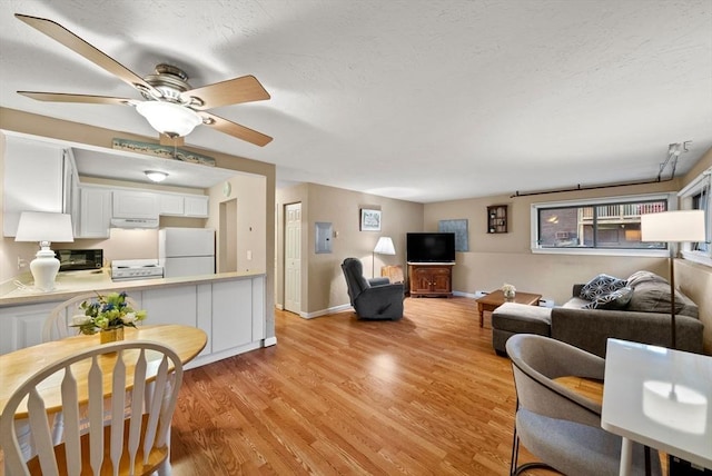 living room with a ceiling fan, baseboards, light wood finished floors, and a textured ceiling