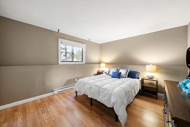 bedroom with baseboards, baseboard heating, and wood finished floors