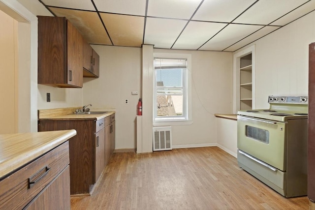 kitchen featuring electric stove, light wood-style floors, a paneled ceiling, light countertops, and a sink