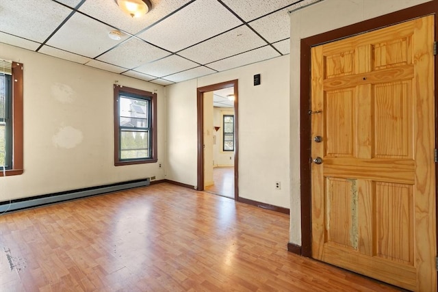 unfurnished room featuring a paneled ceiling, light wood-style floors, baseboards, and a baseboard heating unit