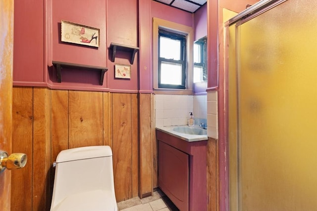 bathroom featuring a shower stall, vanity, wainscoting, wood walls, and toilet