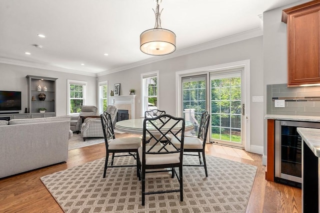 16 Winfield St, Needham, MA 02492 - dining room with wine cooler, ornamental molding, light wood-style flooring, a fireplace, and recessed lighting