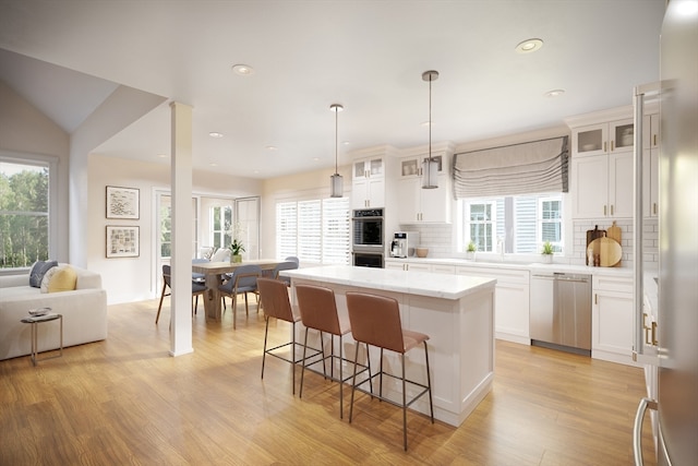 kitchen featuring a kitchen island, stainless steel appliances, white cabinetry, and a healthy amount of sunlight