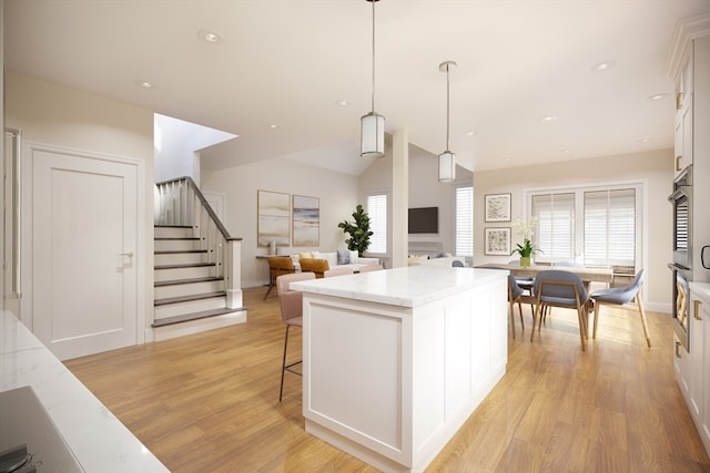 kitchen featuring white cabinets, decorative light fixtures, a center island, and light hardwood / wood-style flooring