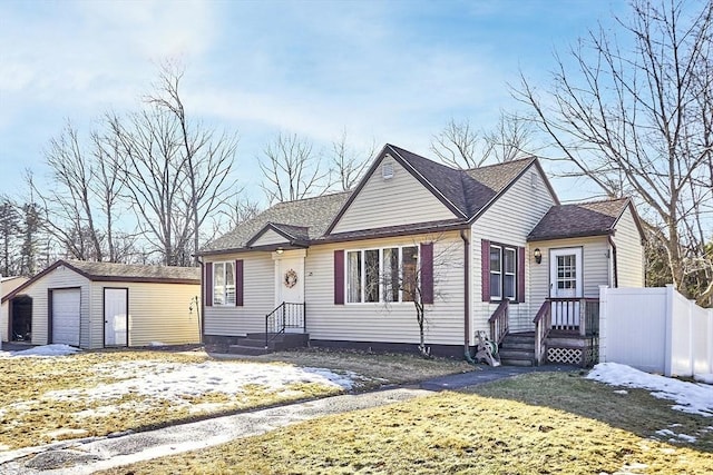 bungalow-style house with an outbuilding, a detached garage, and fence