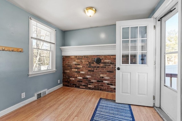 entryway with visible vents, brick wall, baseboards, and wood finished floors