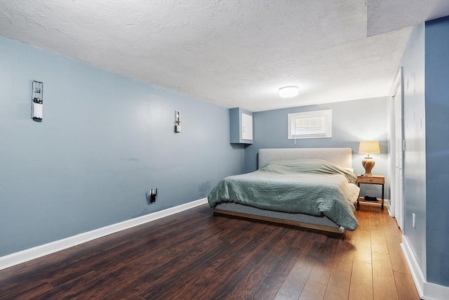 bedroom featuring a textured ceiling, baseboards, and wood-type flooring