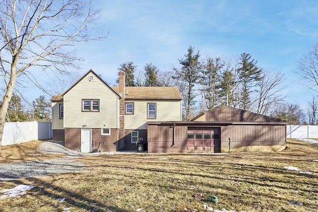 rear view of house featuring driveway, fence, a sunroom, a garage, and a chimney