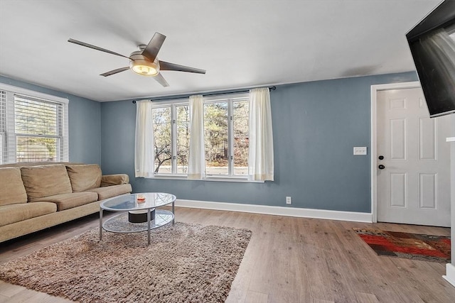 living area featuring ceiling fan, baseboards, and wood finished floors