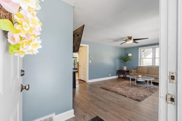 living area featuring ceiling fan, visible vents, baseboards, and wood finished floors