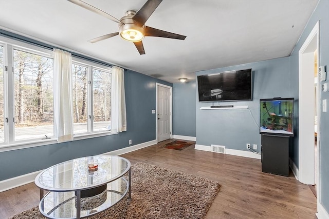 interior space with ceiling fan, wood finished floors, visible vents, and baseboards