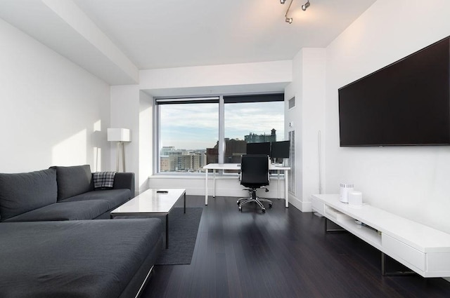 living room with a desk, dark wood-type flooring, and baseboards