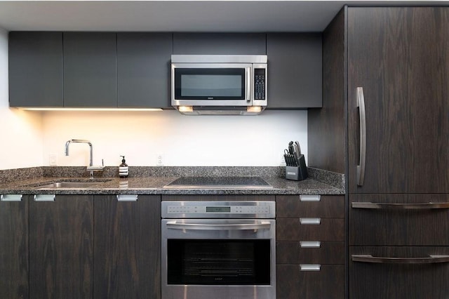 kitchen featuring stainless steel appliances, a sink, dark brown cabinetry, and modern cabinets
