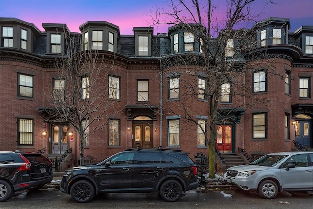 multi unit property with french doors, brick siding, and mansard roof