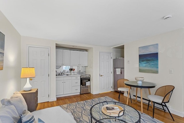 living room featuring light wood finished floors, baseboards, and a baseboard heating unit