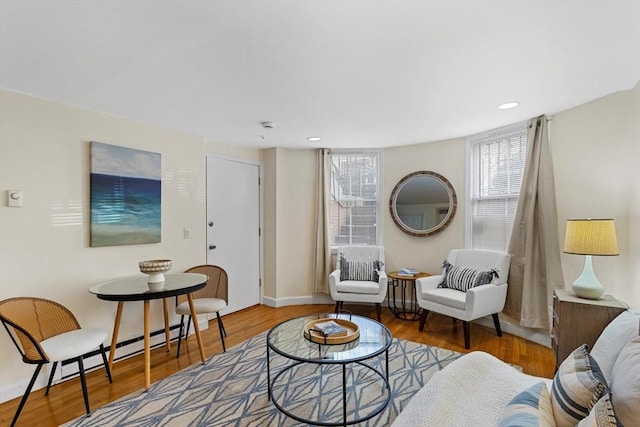 sitting room featuring a baseboard heating unit, recessed lighting, baseboards, and wood finished floors