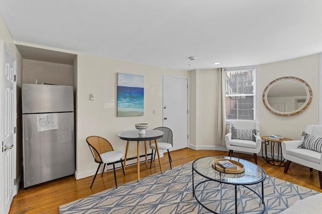 living area featuring a baseboard radiator, baseboards, and wood finished floors