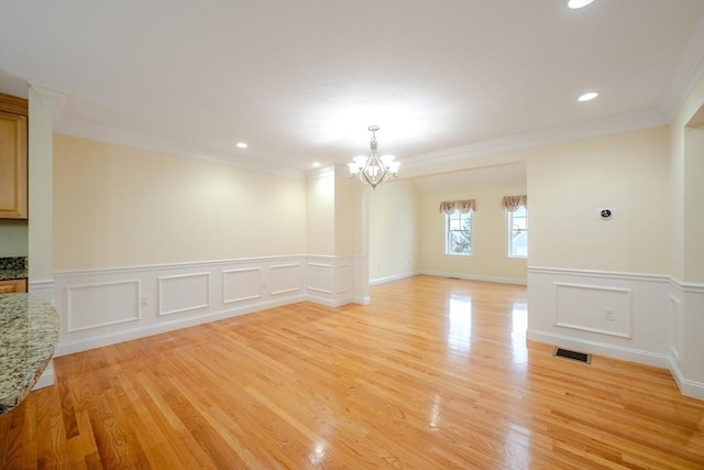 empty room with visible vents, ornamental molding, an inviting chandelier, light wood-type flooring, and recessed lighting