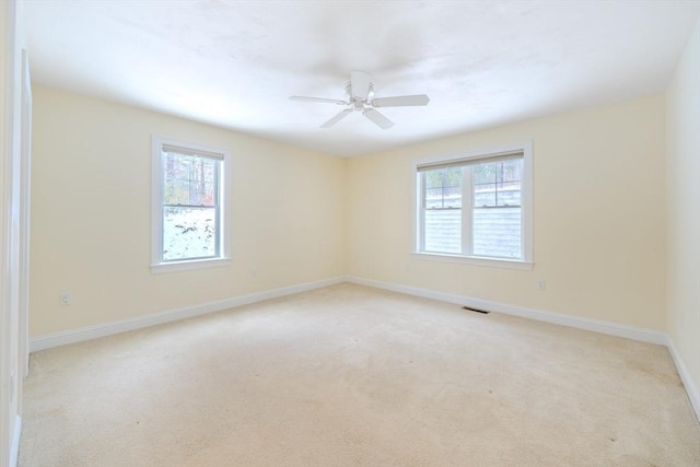 spare room with light colored carpet, a healthy amount of sunlight, and baseboards