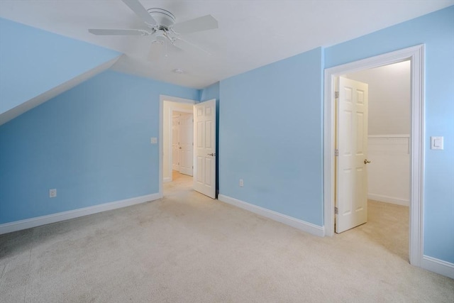 unfurnished bedroom with lofted ceiling, ceiling fan, baseboards, and light colored carpet