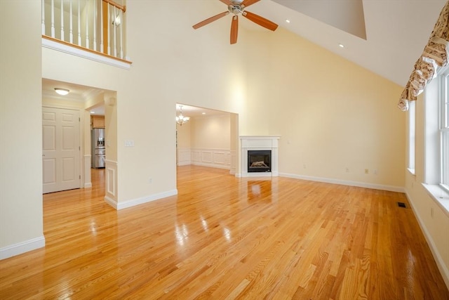 unfurnished living room featuring light wood-type flooring, a fireplace, baseboards, and ceiling fan with notable chandelier