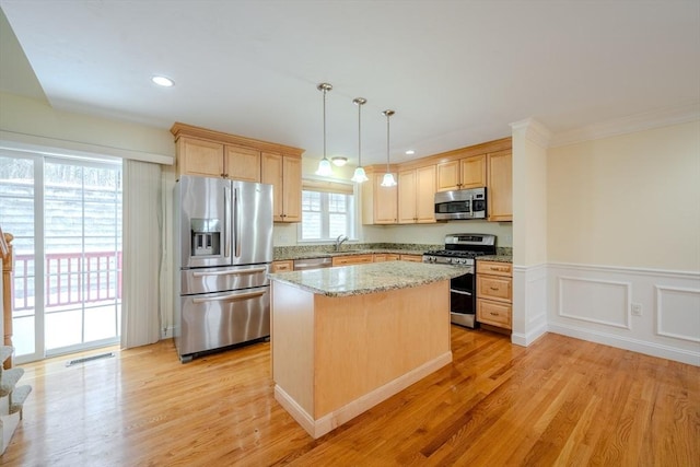 kitchen with stainless steel appliances, a center island, decorative light fixtures, and light brown cabinetry