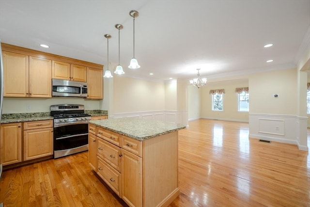 kitchen with light stone counters, a center island, decorative light fixtures, stainless steel appliances, and open floor plan