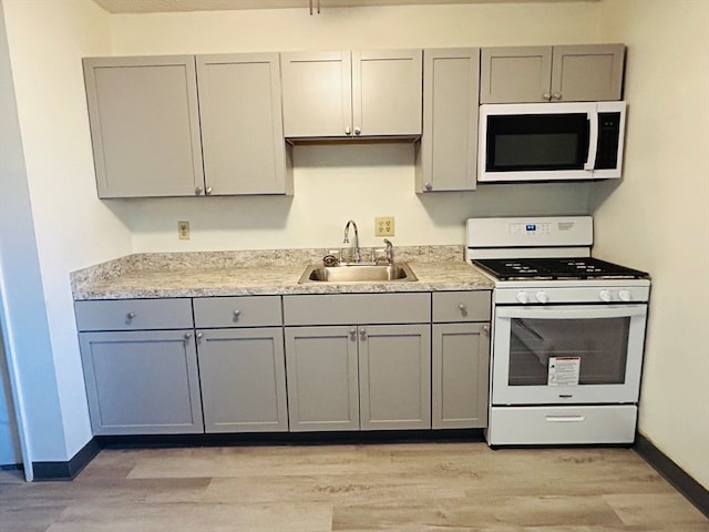 kitchen with light hardwood / wood-style floors, gray cabinetry, sink, and white appliances