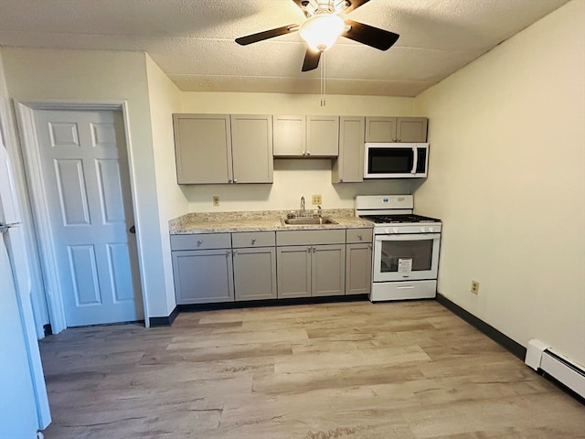 kitchen with white appliances, sink, light wood-type flooring, a baseboard radiator, and ceiling fan